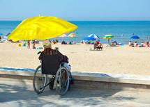a man in a wheelchair looking out at the ocean at the beach 