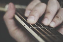 hand on strings on a guitar 