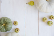 pumpkins, apples, and pears on white wood boards 