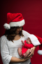 A mother in a Santa hat holding a newborn 