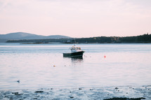 a fishing boat in shallow water by a shore 