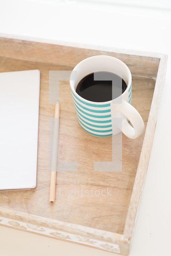 notebook, pencil, and mug on a wooden tray 