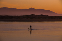 silhouette of a man on a paddle board 