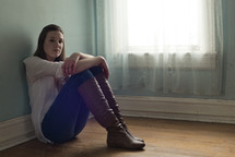 teen girl sitting alone in an empty room 
