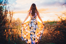 young woman standing in a field at sunset 