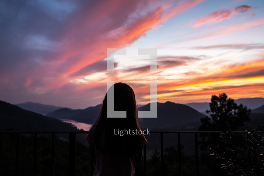 a girl looking out at mountains at sunset 