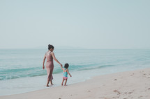 mother and child walking on a beach 
