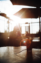 a glass of soda on a table in sunlight 