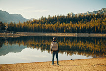A person standing near the shore of a lake.
