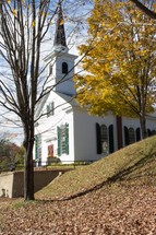 Church surrounded by fall foliage and fallen leaves,