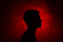 silhouette of a man standing in red light 