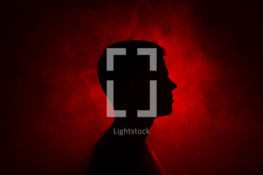 silhouette of a man standing in red light 
