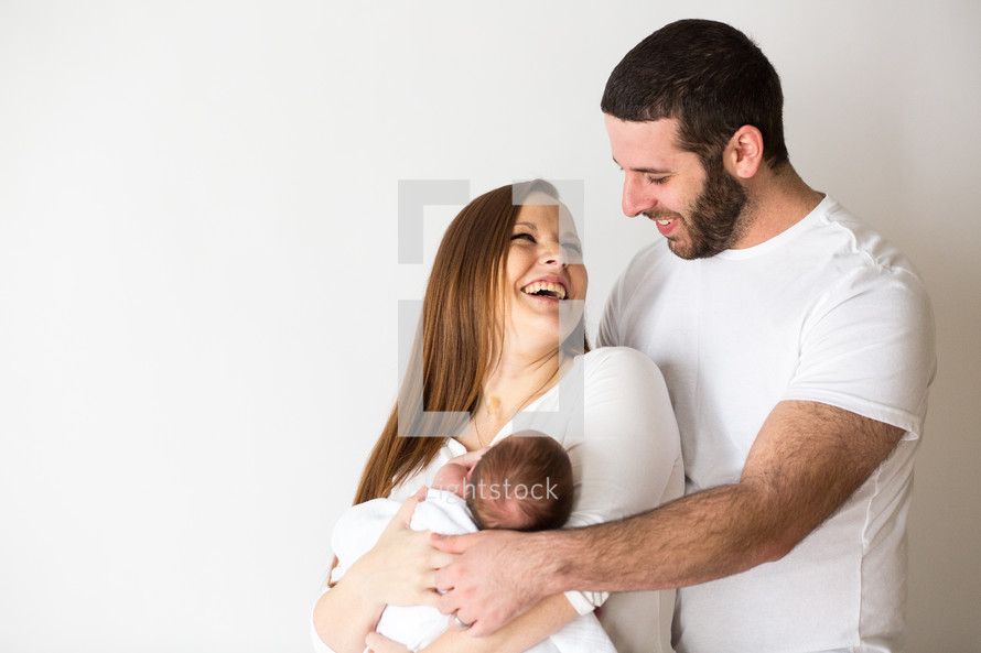 portrait of new parents holding their newborn 