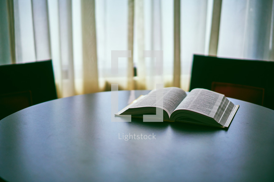 Open bible on a table between two chairs