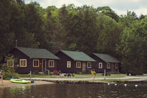 Vintage cabins in a row by a lake.