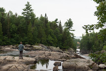 a man standing on rocks near a stream 