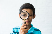 boy child looking through a magnifying glass 