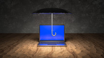 Black umbrella hovering over computer on wooden table
