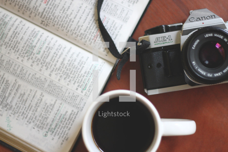 coffee mug, camera, and open Bible