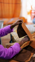 Woman holding up a leather wallet in a leather workshop