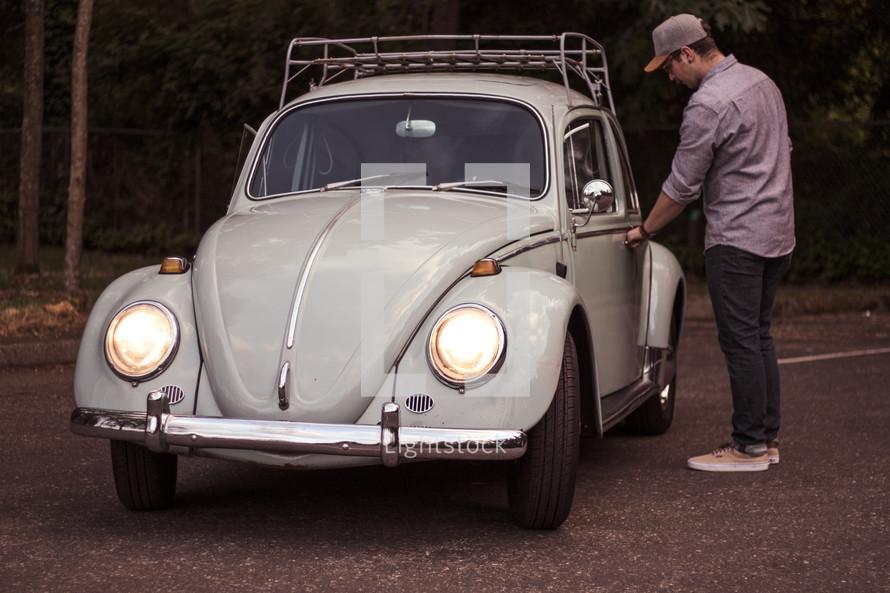 a man opening the door of a vintage Volkswagen Beetle 