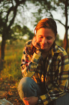 a smiling woman outdoors in a plaid shirt 