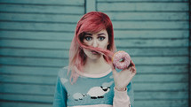 a young woman with pink hair holding a donut 