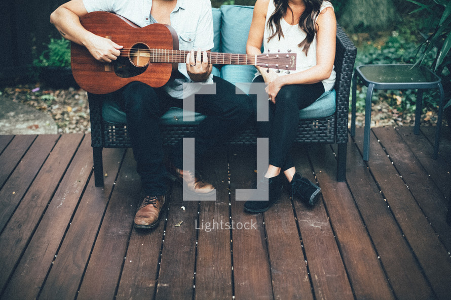 couple sitting on a bench and a man playing a guitar 