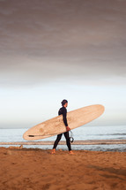 surfer walking on a beach 