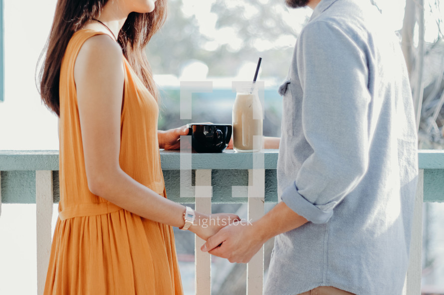 a couple holding hands standing in front of a cafe window 
