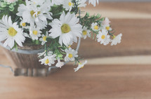 a wooden bucket full of white daisies 