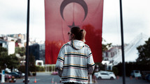 a woman standing in the street and the Turkish flag in the background 