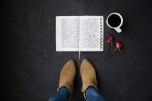 feet standing beside and open Bible, dried, roses, and coffee cup 