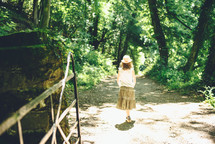 a girl walking on a path in the woods 