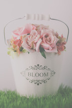 pink roses in a white pail on grass