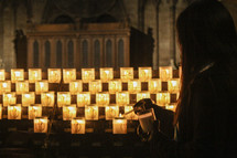 a woman lighting a candle in a cathedral 