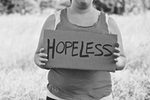 woman holding a sign that reads hopeless