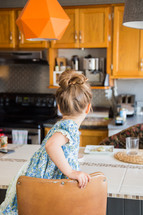 child sitting in a stool in a kitchen 