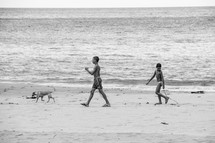 children and a dog walking on a beach 