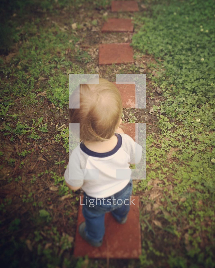 toddler boy standing on stepping stones 