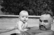 father and infant son swimming in a pool 