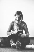A woman reading to a child in her lap.
