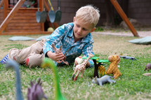 a kid playing with toy animal figurines in grass