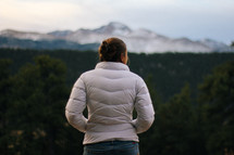 a woman looking out at snow on a mountain 