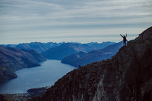 woman standing on a mountaintop with raised hands 