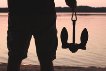a man holding an anchor on a shore