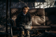 a boy sitting on a chair outdoors 