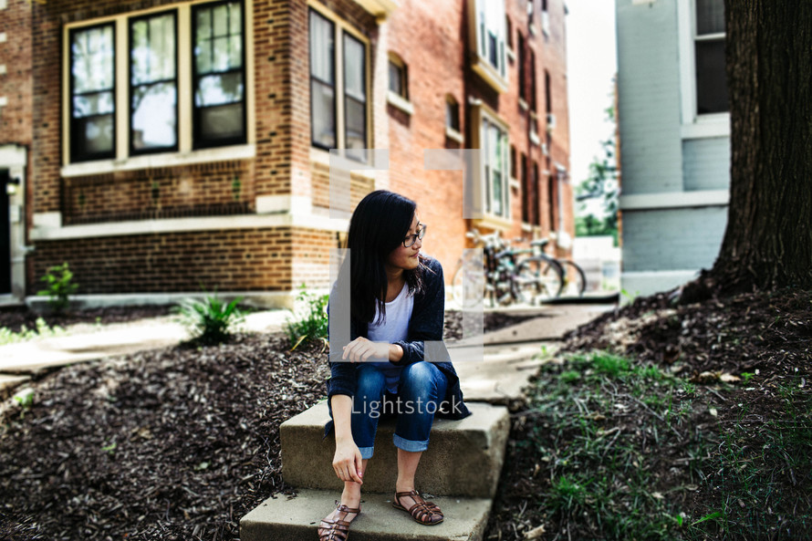 young woman sitting on steps outdoors 