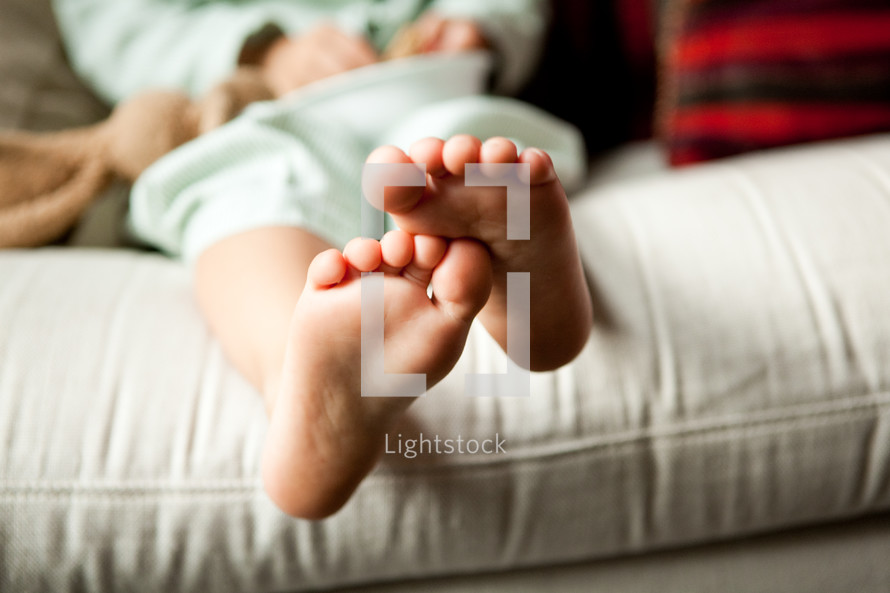 toddlers bare feet sitting on a couch 