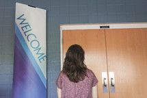 woman standing by a welcome sign 